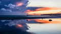 Dark storm clouds above an orange sunset reflected in still water on the Sussex coast – photograph by Sharon Maskery