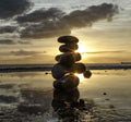 Balanced stones silhouetted against a golden sunset on the Sussex coast – original photography by Sharon Maskery